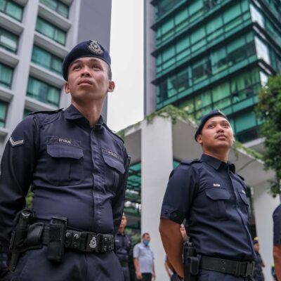 Police standing in front of a building in Kuala Lumpur.