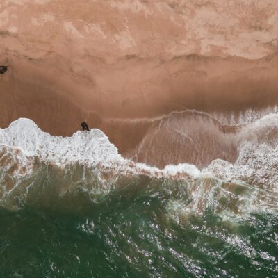 Aerial view of waves crashing on a sandy shore.