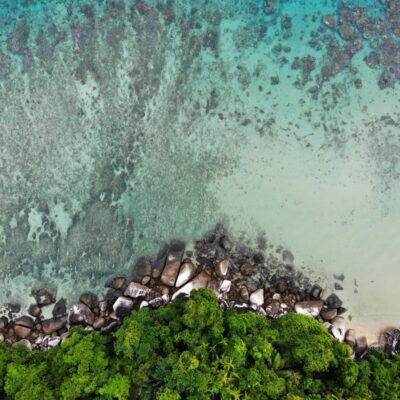 Part of a coastline of Malaysia with tropical forest, rocks on the shore and the ocean.