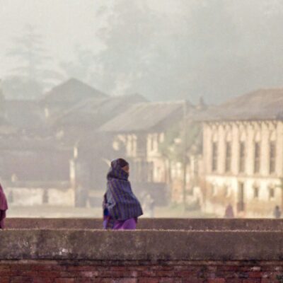 Three women walk on a wall in Kathmandu, 2026.