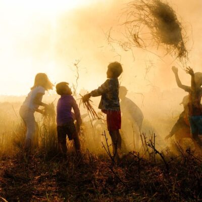 Silhouette of a groups of children playing in a field.